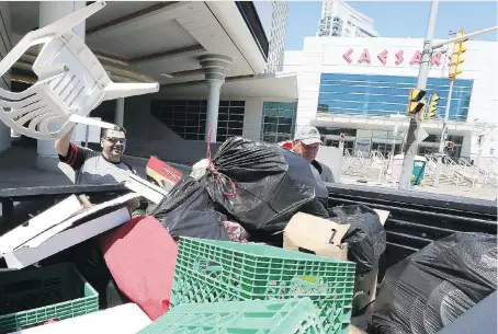  ?? NICK BRANCACCIO ?? Unifor Local 444 members Frank Safou, left, and Tim Jarrold pick up items of clothing and lawn chairs outside Caesars Windsor after union members voted in favour of a new contract on Monday. The casino announced new dates for five concerts that had...