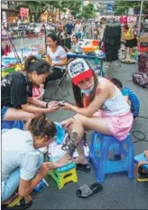  ??  ?? Street vendors are allowed after 7 pm every day in Yibin’s East Street, Sichuan province. A girl has her nails done by a manicurist.