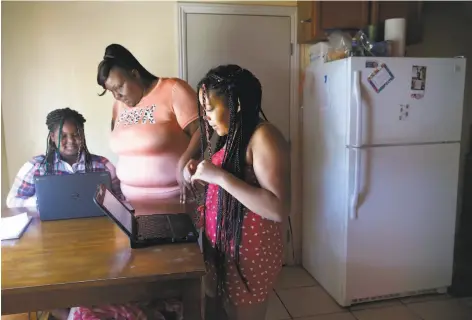  ?? Paul Chinn / The Chronicle ?? Michelle Burnett helps daughters Namarhiann­a (left), 9, and Alayjah, 12, with online schoolwork at their home in Vallejo.