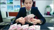  ?? ZHANG YUN / CHINA NEWS SERVICE ?? A clerk counts cash at a bank outlet in Taiyuan, Shanxi province.