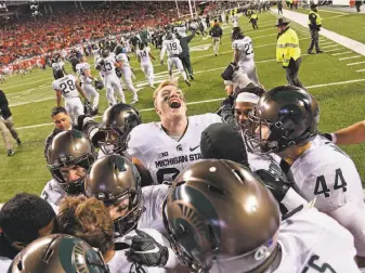  ?? Jamie Sabau / Getty Images ?? Michigan State players crowd around kicker Michael Geiger after Geiger's 41-yard field goal defeated Ohio State 17-14 at Ohio Stadium in Columbus on Saturday.