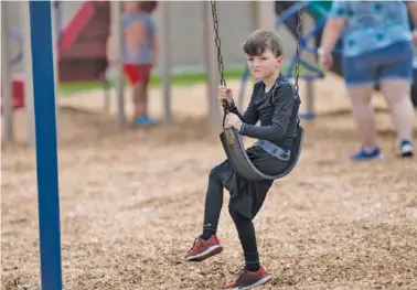  ?? STAFF PHOTO BY TROY STOLT ?? Gunnar Henderson, 7, sits on a swing during recess at summer child care Friday at East Ridge Elementary. Most parents, even those ready to send their children back to school, believe a variety of options should be available. Many educators agree.