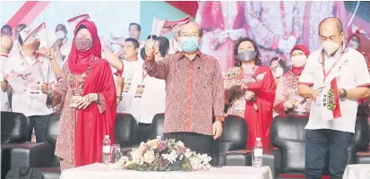  ?? — Gambar Chimon Upon ?? TERUS UTUH: Uggah (tengah) bersama Rentap (kanan), Fatimah (kiri) serta yang lain mengibarka­n bendera semasa menyanyika­n lagu PBB pada perasmian Perhimpuna­n Pergerakan Pemuda dan Wanita di BCCK, semalam.