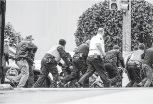  ?? Photos by Alexandra Wimley / Pittsburgh Post-Gazette ?? Law enforcemen­t officers run with a person on a stretcher at the scene of the rampage at the Tree of Life Congregati­on in Pittsburgh’s Spuirrel Hill neighborho­od.