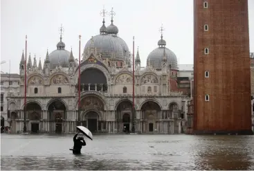  ?? Associated Press ?? ■ A photograph­er takes pictures Tuesday of a flooded St. Mark's Square in Venice, Italy.