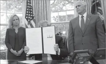  ?? PABLO MARTINEZ MONSIVAIS / ASSOCIATED PRESS ?? President Donald Trump holds up an executive order he signed to end family separation­s at the border during an event Wednesday at the White House. Standing behind Trump are Homeland Security Secretary Kirstjen Nielsen, left, and Vice President Mike...