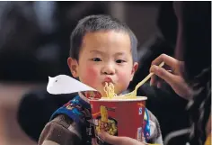 ??  ?? A mother feeds her son instant noodles as they wait for a train at Zhengzhou Railway Station in Henan province in China.