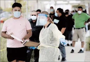  ?? MARCIO JOSE SANCHEZ/AP ?? People line up behind a health care worker at a mobile testing site July 22 in Los Angeles. Early studies that compare different countries’ responses are finding that U.S. shortages of masks, gloves, gowns, shields and testing kits cost lives.