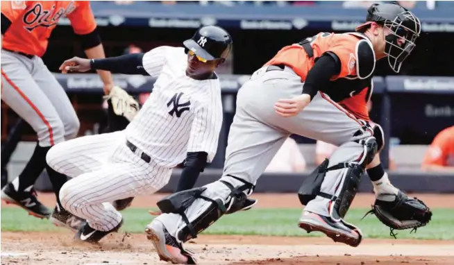  ??  ?? NEW YORK: New York Yankees shortstop Didi Gregorius, left, slides past Baltimore Orioles catcher Caleb Joseph to score on a sacrifice fly by Austin Romine during the second inning. — AP