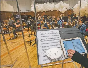  ??  ?? Giuseppe Verdi jazz orchestra musicians and singers play behind a transparen­t panel during a rehearsal.