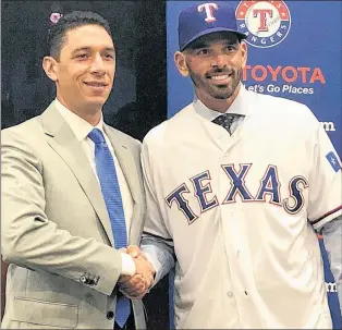  ?? AP PHOTO ?? Texas Rangers’ general manager Jon Daniels shakes hands with new manager Chris Woodward during a press conference Monday in Arlington, Texas.