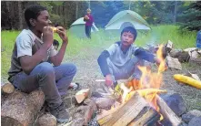  ?? THOMAS PEIPERT/ASSOCIATED PRESS ?? Justin Mbelechi, 13, and Bidesh Magar, 14, roast corn at their campsite in Evergreen, Colo., in September. The two belong to a Colorado Boy Scout troop that is made up almost entirely of refugees.