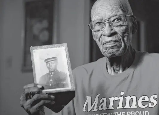  ?? Photos by Melissa Phillip / Staff photograph­er ?? Arthur Jackson, 99, holds a photo of himself in his Marine uniform. Serving from 1942 through 1946, Jackson was one of the original Montford Point Marines.