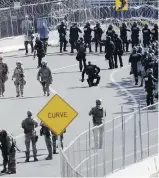  ??  ?? U.S. military personnel and customs officers gather along the port of entry in San Diego, California. At least 3,000 people have recently arrived in Tijuana, Mexico, across the border from San Diego, with hopes of requesting asylum.