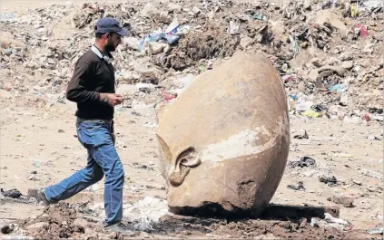  ?? PHOTO: REUTERS ?? Royal ear . . . A man passes by the head of an unearthed statue that workers say depicts Pharaoh Ramses II, in Cairo, Egypt.