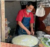  ??  ?? A man makes a crepe on a Shanghai side street.