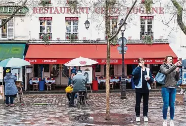  ?? Bloomberg ?? Protests halt spending: Tourists take selfies as artists draw portraits outside cafes in Paris. Household spending has also ground to a halt in France, which is beset by the Yellow Vest protests.—