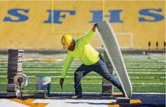  ?? PHOTOS BY JIM WEBER THE NEW MEXICAN ?? LEFT: Francisco Rojo cuts strips of adhesive to place letters in the end zone.