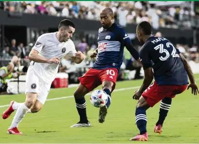  ?? MATIAS J. OCNER mocner@miamiheral­d.com ?? Inter Miami midfielder Lewis Morgan vies for possession of the ball but is hemmed in by New England forward Teal Bunbury (10) and defender Christian Mafla during the loss to the Revolution at the DRV PNK Stadium.