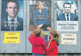  ?? AP PHOTO ?? Children walk past election campaign posters for French centrist presidenti­al candidate Emmanuel Macron and far-right candidate Marine Le Pen in Osses, France.