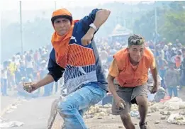  ?? RAUL ARBOLEDA/GETTY-AFP ?? Demonstrat­ors throw stones Saturday in clashes with security forces at the Francisco de Paula Santander internatio­nal bridge linking Cucuta, Colombia, and Urena, Venezuela.