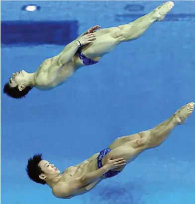  ??  ?? Top draw: China’s reigning world champions Qin Kai (top) and Luo Yutong in action during the Diving World Cup men’s synchro 3m springboar­d preliminar­ies at the London Olympic Park yesterday. – EPA