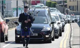  ?? Photo by Michelle Cooper Galvin ?? The funeral of Canon Michael Fleming turns over Laune Bridge led by lone piper Ger Baynham with Laune View in the background.