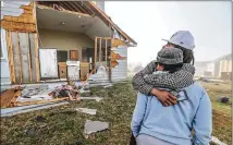  ??  ?? Ontario Alvarez holds his mother, Katrina Dawson, in front of their house on Jumpers Trail as they survey the damage from the March 20 storm that included a tornadoes and hail