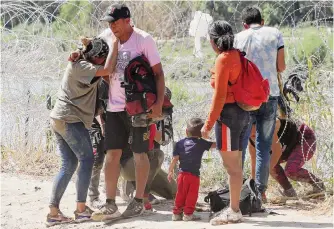  ?? Jerry Lara/staff photograph­er ?? Migrants get through concertina wire lining the banks of the Rio Grande in Eagle Pass. The Pew Research Center analyzed data, finding a significan­t shift in migrants’ country of origin.
