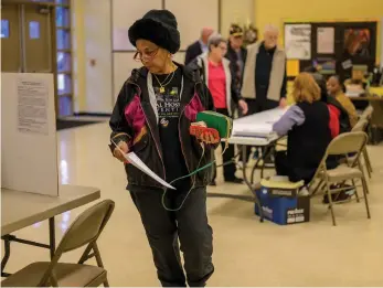  ?? Staff photo by Hunt Mercier ?? ■ Sandra Young prepares to vote Tuesday while others behind her wait to acquire a ballot at the Pleasant Grove Middle School band hall in Texarkana, Texas. Jay Davis defeated Mike Ingram, 401 votes to 326, to represent Ward 6, according to complete but unofficial results. He will be sworn in after an official canvass of the votes during a special Council meeting at 12:30 p.m. Feb. 7 in City Hall.