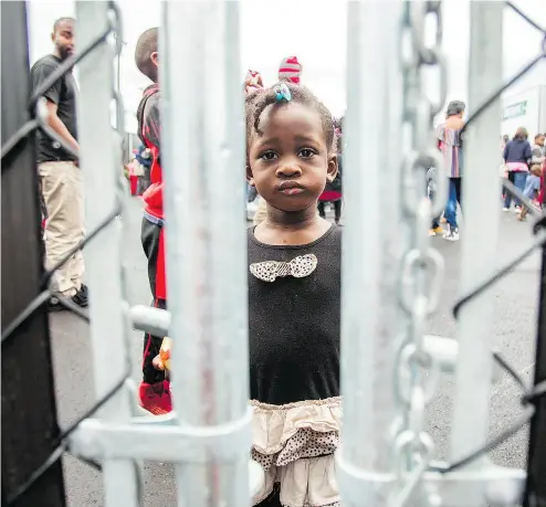  ?? GEOFF ROBINS / AFP / GETTY IMAGES FILES ?? A girl who crossed the Canada-U. S. border illegally with her family, claiming refugee status in Canada, looks through a fence at a temporary detention centre in Blackpool, Que., on Aug. 5. Fewer claimants are gaining refugee status.