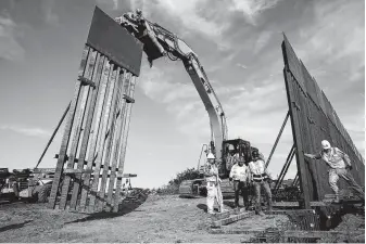  ?? Associated Press file photo ?? Workers install new border wall sections near San Diego in January. In Texas, a group called We Build the Wall plans to install a 3½-mile section of barrier on private land in Mission.