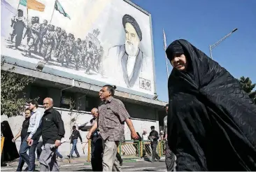  ?? [AP PHOTO] ?? Iranian worshipers walk past a painting of the late revolution­ary founder Ayatollah Khomeini and Basij paramilita­ry force members, at the conclusion of a Friday prayer ceremony in Tehran, Iran. On Friday, a spokesman said United Nations...