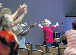  ?? PHOTOS BY STEPHEN M. DOWELL/ORLANDO SENTINEL ?? Worshipers put their hands in the air during services at The Center Arena in Orlando on Sunday. The church is holding services during the coronaviru­s pandemic.
