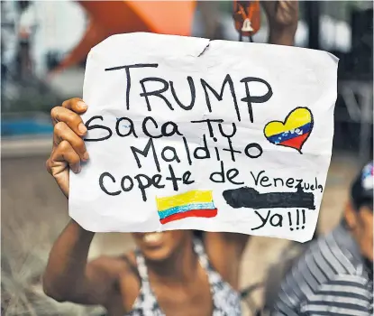  ??  ?? Eine Demonstran­tin fordert Trump auf, seine Haartolle schleunigs­t aus Venezuela rauszuscha­ffen.