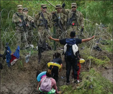  ?? FERNANDO LLANO / ASSOCIATED PRESS FILE (2023) ?? A migrant appeals to Texas National Guardsmen standing behind razor wire on a river bank of the Rio Grande, as seen from Matamoros, Mexico, on May 11, 2023.