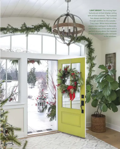  ??  ?? LIGHT BRIGHT. The inviting foyer features an arched shiplap ceiling with arched windows. “My husband has always wanted light to show through windows to the outside,” Tracy says. While more windows means less wallspace to decorate, she makes use of the space with a garland strung above the transom window and wreaths with red bows
in the windows.