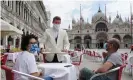  ??  ?? A waiter serves two tourists at the outdoor tables of the Caffe Quadri on St Mark’s square. Photograph: Andrea Merola/EPA