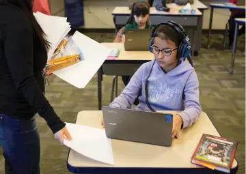  ?? PHOTOS BY OLIVIA HARLOW/THE NEW MEXICAN ?? Third-grade student Jocelin Castillo receives papers and pencils before taking the PARCC test Wednesday at El Camino Real Academy.