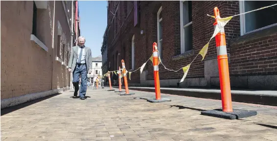  ??  ?? Victoria Coun. Geoff Young walks Waddington Alley, the last remaining stretch of city street paved with wooden blocks. The blocks are being refurbishe­d in a painstakin­g project.