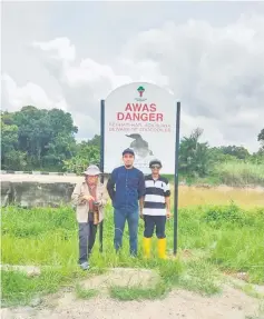  ??  ?? Staff of National Parks and Wildlife Division in front of a crocodile warning sign at Kampung Tisak Ulu in Betong.