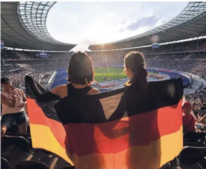  ?? FOTO: ?? Zwei Fans mit Deutschlan­dfahne stehen auf der Tribüne des Berliner Olympiasta­dions.