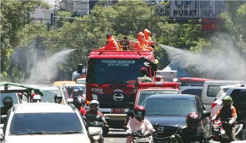  ?? DIMAS MAULANA/JAWA POS ?? SEMPROT SEMUA KAWASAN: Petugas BPBD Sidoarjo melakukan penyemprot­an cairan disinfekta­n di Jalan Gajah Mada dengan mobil pemadam kebakaran (damkar) kemarin.