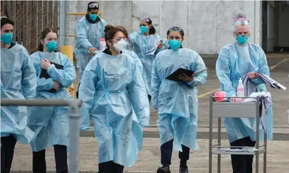  ?? Photograph: Luis Ascui/AAP ?? Health workers at a drive-through Covid vaccinatio­n centre in Melbourne. Academics are calling for 90% of all Australian­s to be vaccinated before the country opens up.