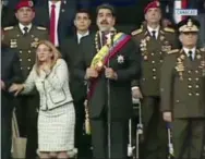  ?? VENEZOLANA DE TELEVISION VIA AP ?? In this still from a video provided by Venezolana de Television, Presiden Nicolas Maduro, center, delivers his speech as his wife Cilia Flores winces and looks up after being startled by an explosion, in Caracas, Venezuela, Saturday.