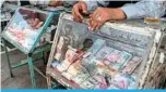  ?? — AFP ?? KABUL: Customers at a money exchanger in Kabul.