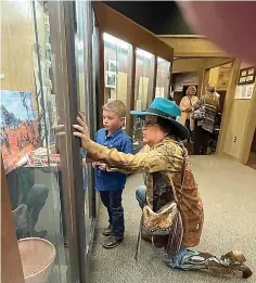  ?? (Photo by Neil Abeles) ?? Here’s what a museum is for. Sandra Parker from New Boston gets down on her knees to allow the young boy to show her something he sees and either knows about or wants to know about. They are looking at a display of a Caddo Indian village.