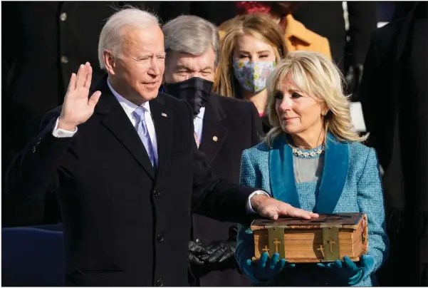  ?? (AP/Andrew Harnik) ?? President Joe Biden takes the oath of office Wednesday from Chief Justice John Roberts on the Capitol steps as his wife, Jill, holds the Bible that has been in the Biden family for 128 years.