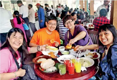  ??  ?? A group of Chinese tourists enjoying local delicacies at the ‘Hela Bojun Hala’ in Nuwara Eliya. This restaurant offers all kinds of local food. Pic by Shelton Hettiarach­chi, Nuwara Eliya correspond­ent.