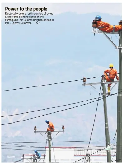  ??  ?? Power to the people Electrical workers resting on top of poles as power is being restored at the earthquake-hit Balaroa neighbourh­ood in Palu, Central Sulawesi. — AP